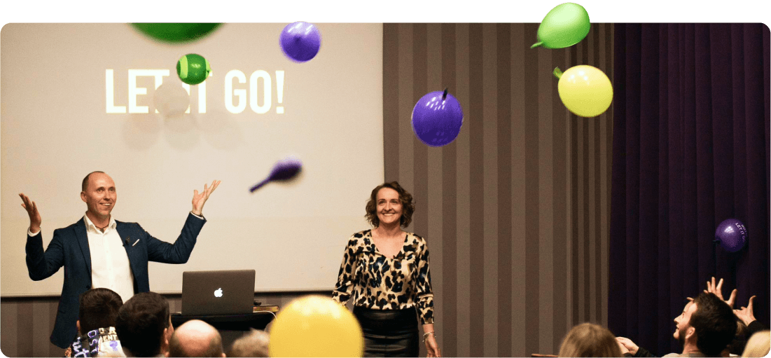 Sylvia and Tom Kornas laughing with a crowd as balloons fall