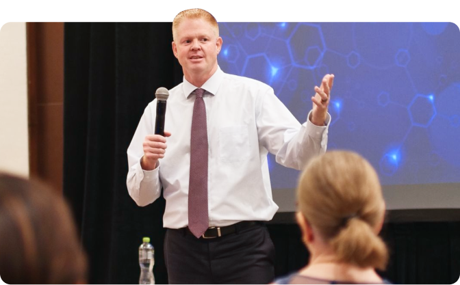 Brian Matsen speaking into a microphone at an event.